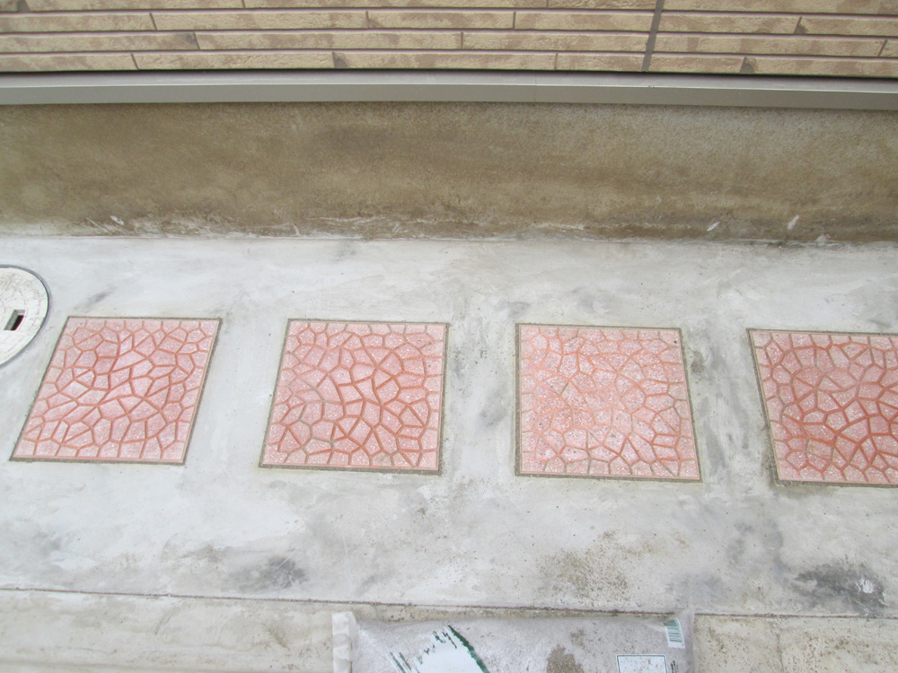 砂利が敷いてあった建物の隅の花壇を、土間コンクリート打ちにして中央にタイルを敷設しました。